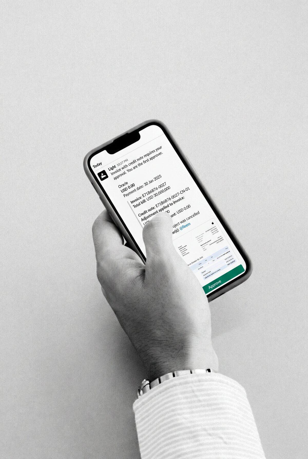 A hand holding a phone with a bill approval from Light in Slack