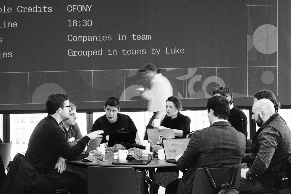 Teams being briefed on stage at a Finance Hackathon