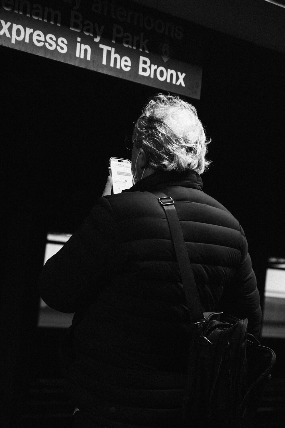 A commuter reading their phone beneath a subway sign