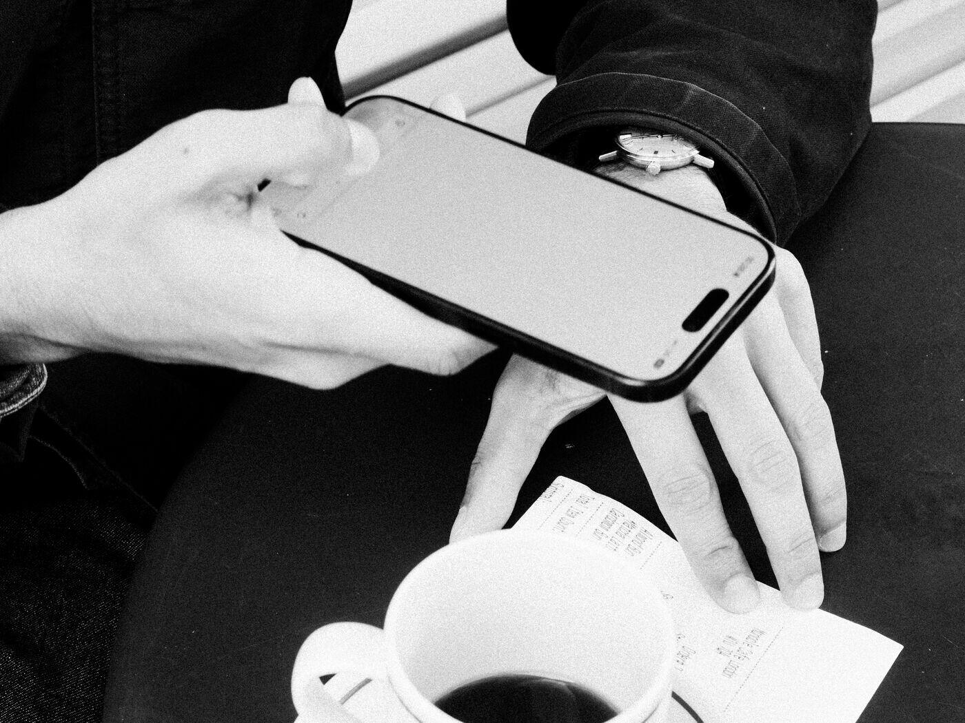 Photographing a paper receipt with a phone over a coffee