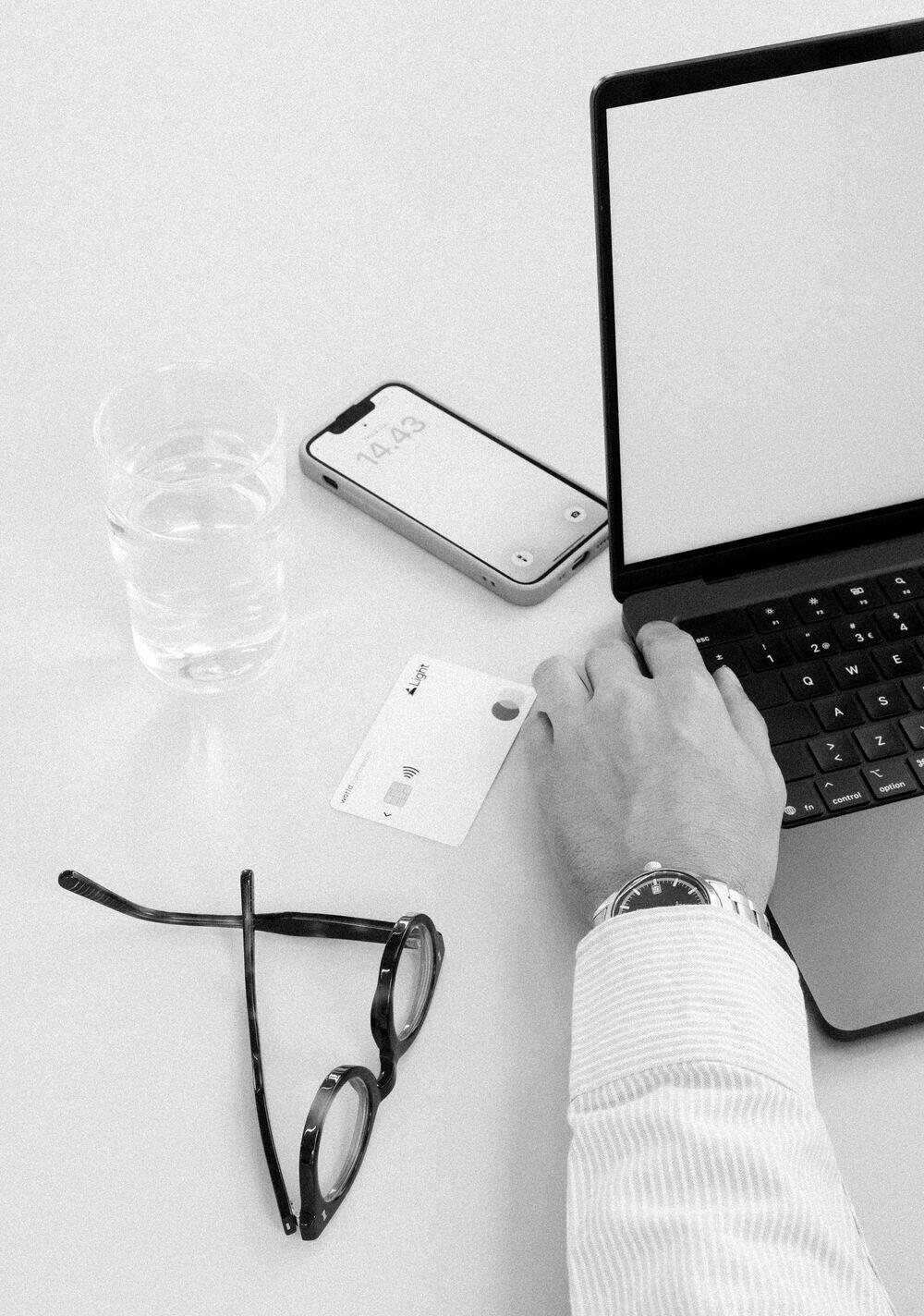 A Light card on a desk beside a laptop, phone, and glasses
