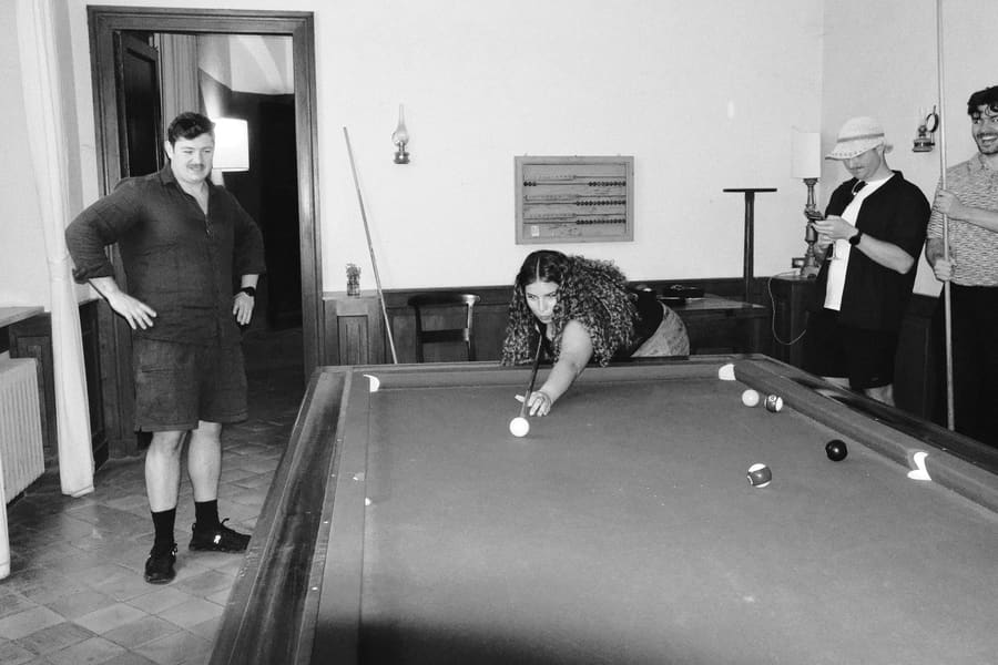 A teammate lining up a pool shot while others look on