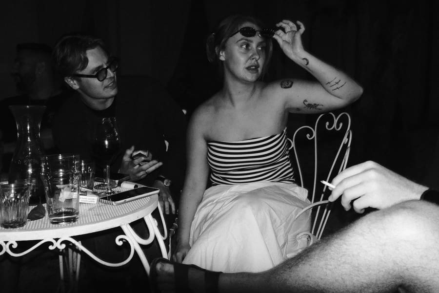 A teammate lifting her sunglasses while chatting at a candlelit table