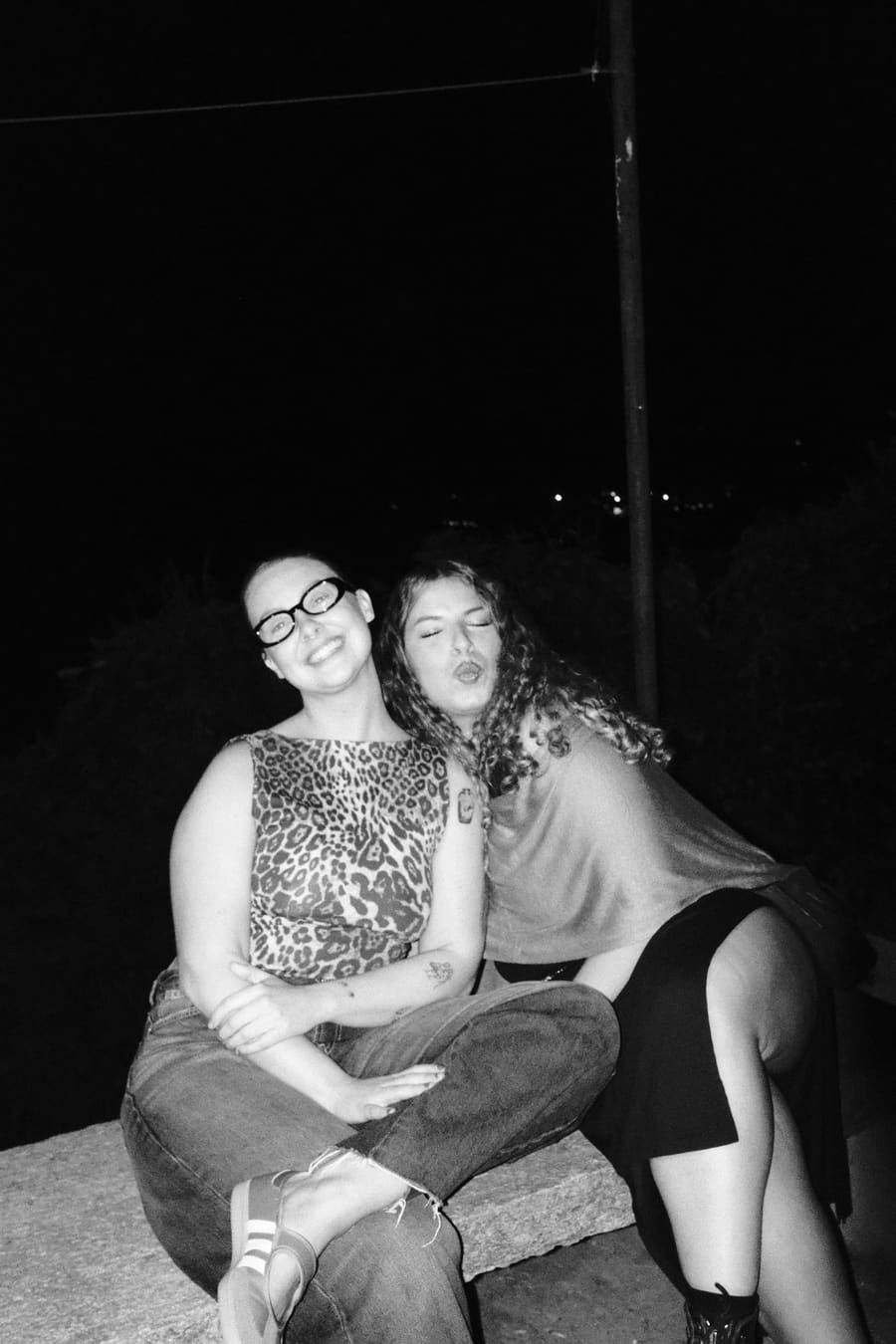 Two teammates posing together on a stone ledge at night