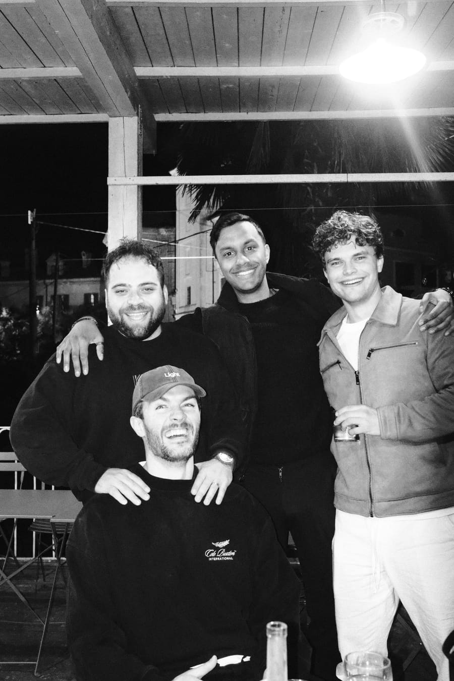 Four teammates smiling together at night, one wearing a Light cap