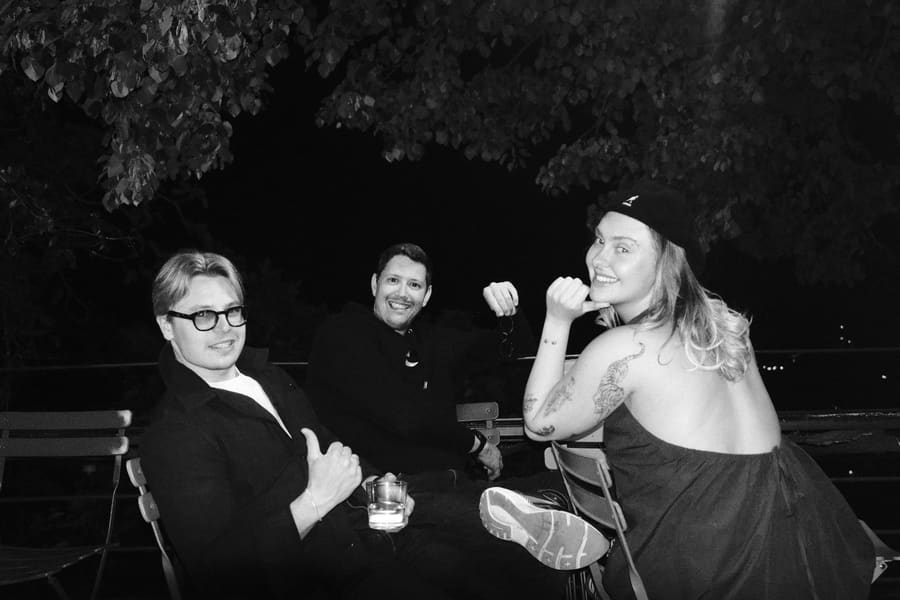 Three teammates sitting together at an outdoor table at night