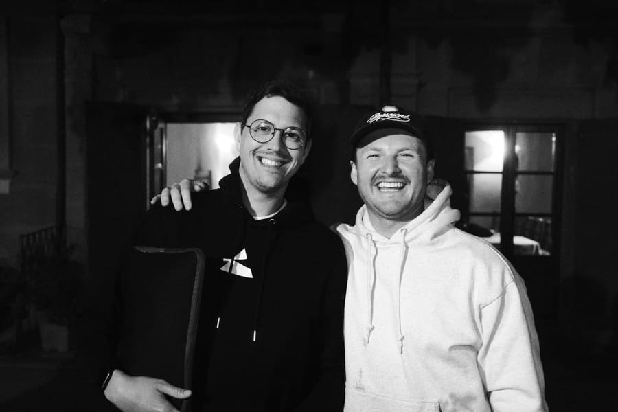 Two teammates with arms around each other, smiling at night