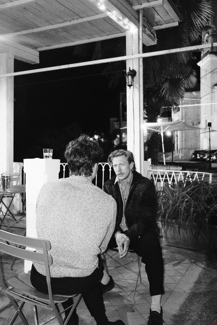 Two teammates in conversation on a lit patio at night