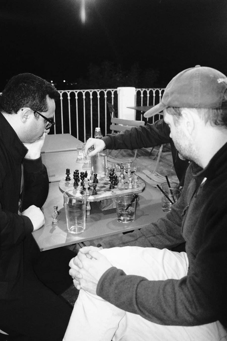 Two teammates playing chess at an outdoor table at night