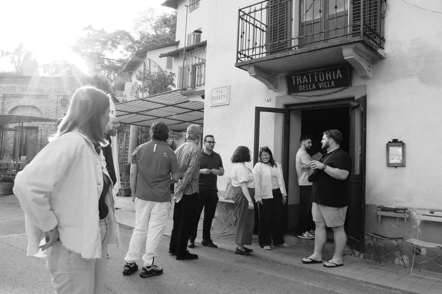 Teammates chatting outside a trattoria storefront in the evening light