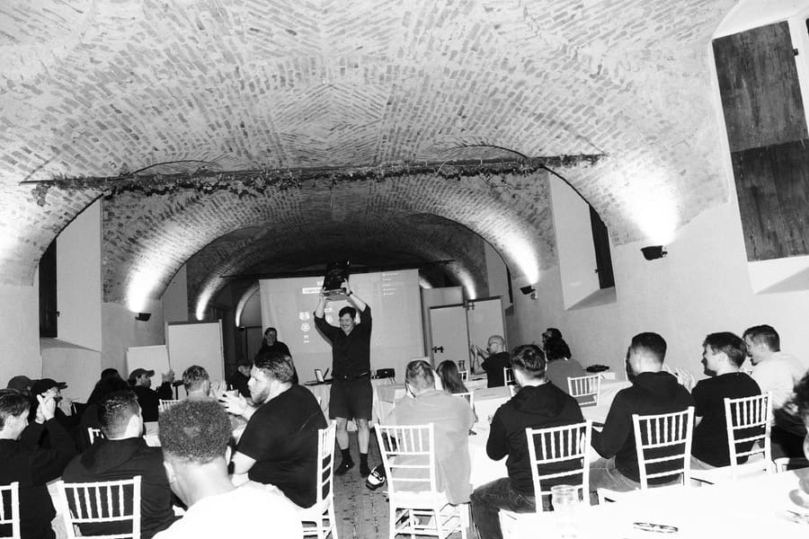 A teammate raising a trophy overhead to applause in a vaulted brick room