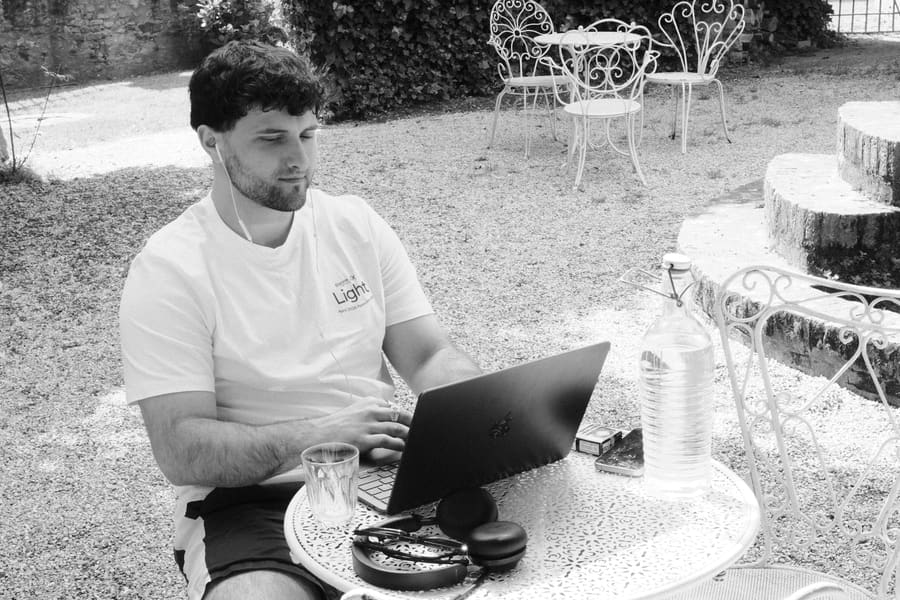 A teammate in a Light t-shirt working on a laptop at an outdoor table