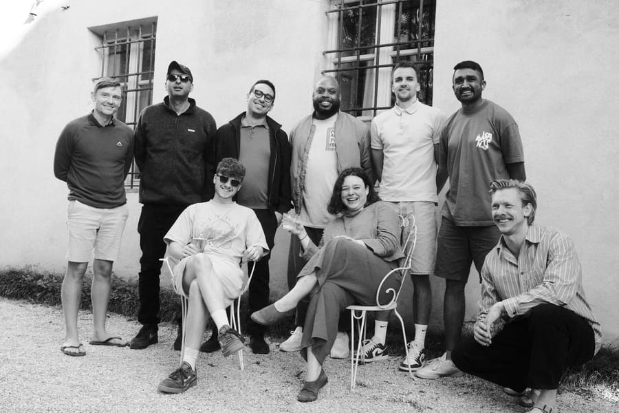 Group team photo posed outside a stone villa