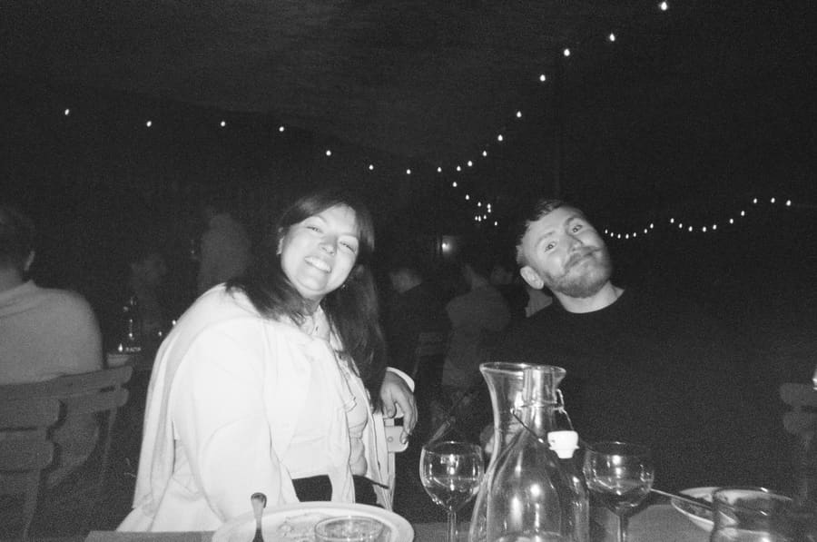 Two teammates smiling at a candlelit dinner table at night
