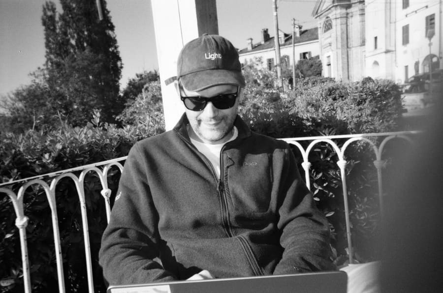 A teammate in a Light cap and sunglasses working on a laptop in the sun