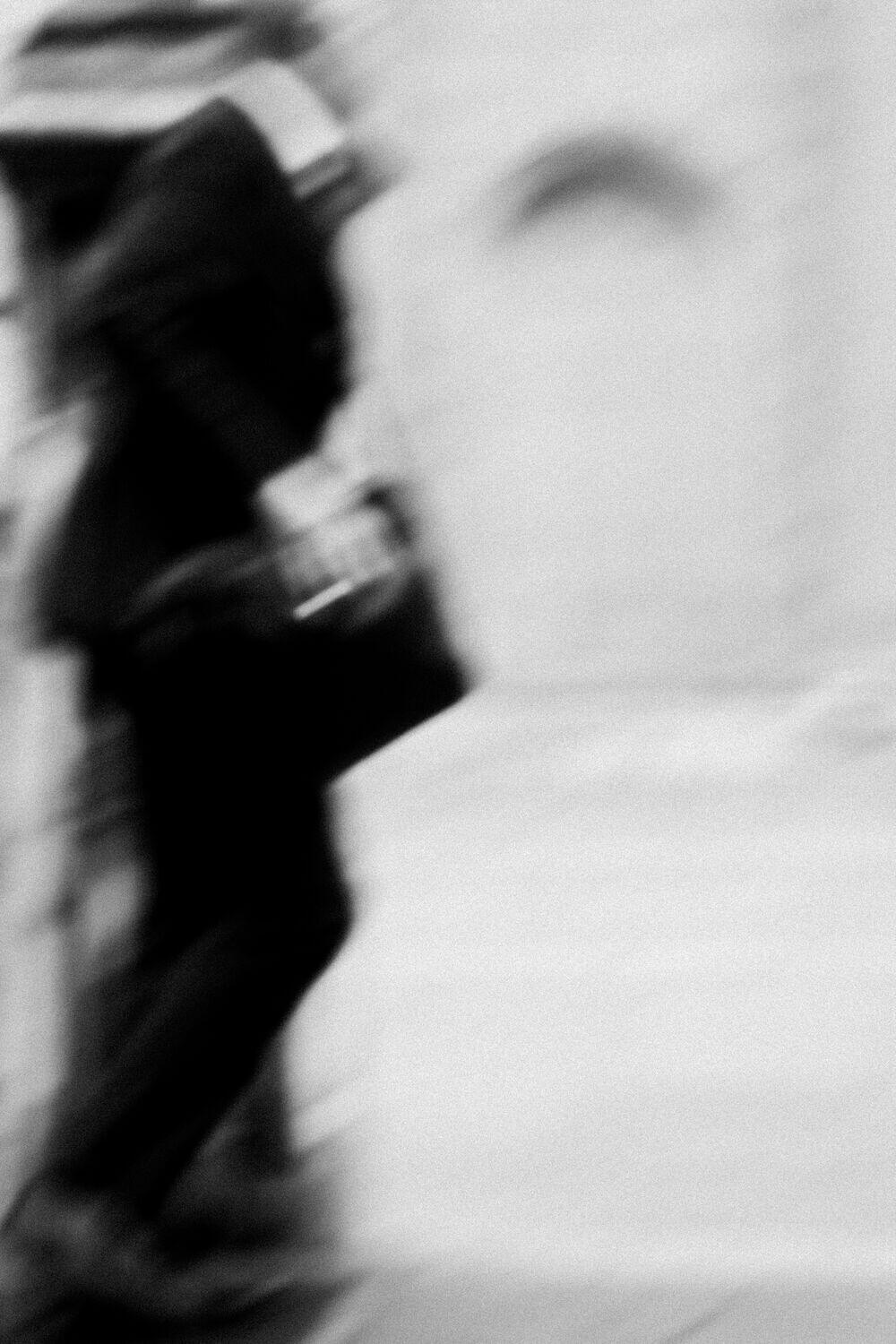 A figure walking past a stone wall, motion-blurred
